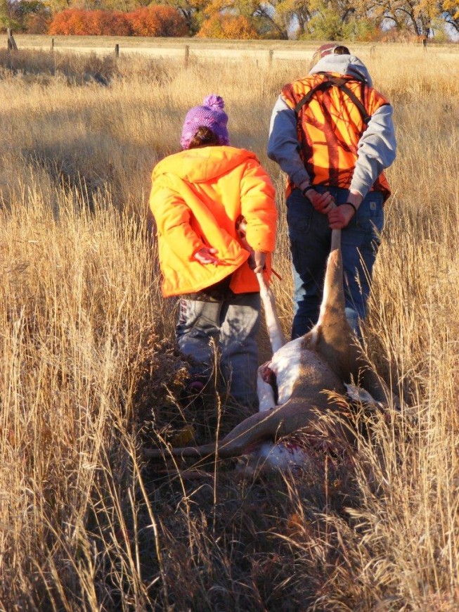 adult and child dragging a deer